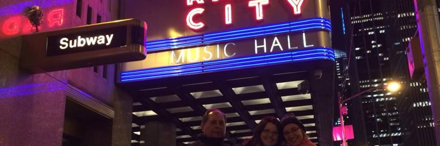 people posing under Radio City Music Hall sign in NYC